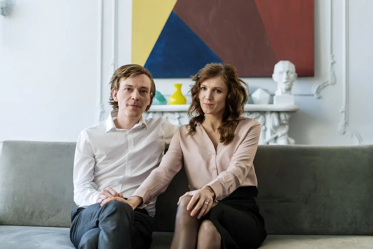Couple sitting on couch facing forward.